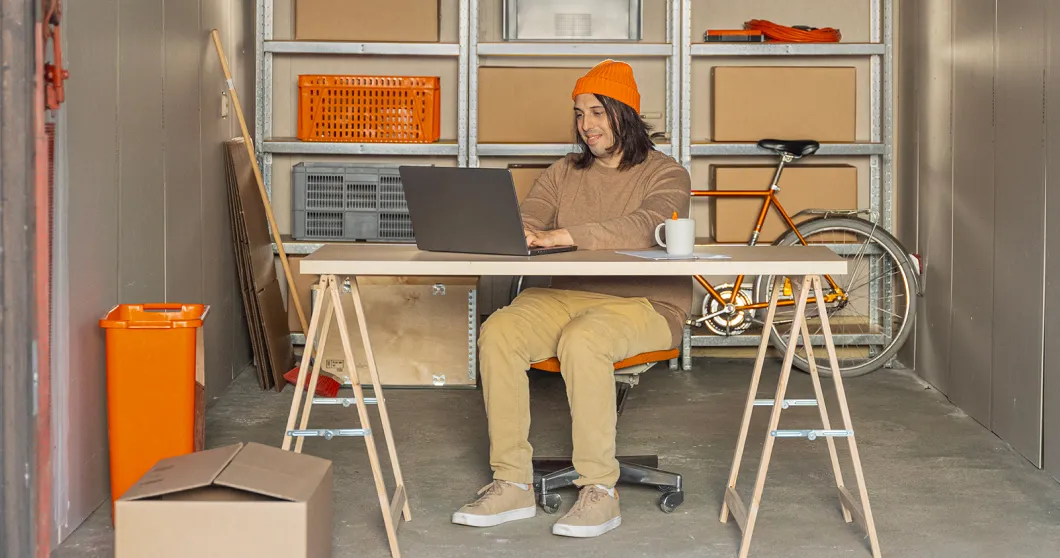 Man zit in een garage en werkt op zijn laptop