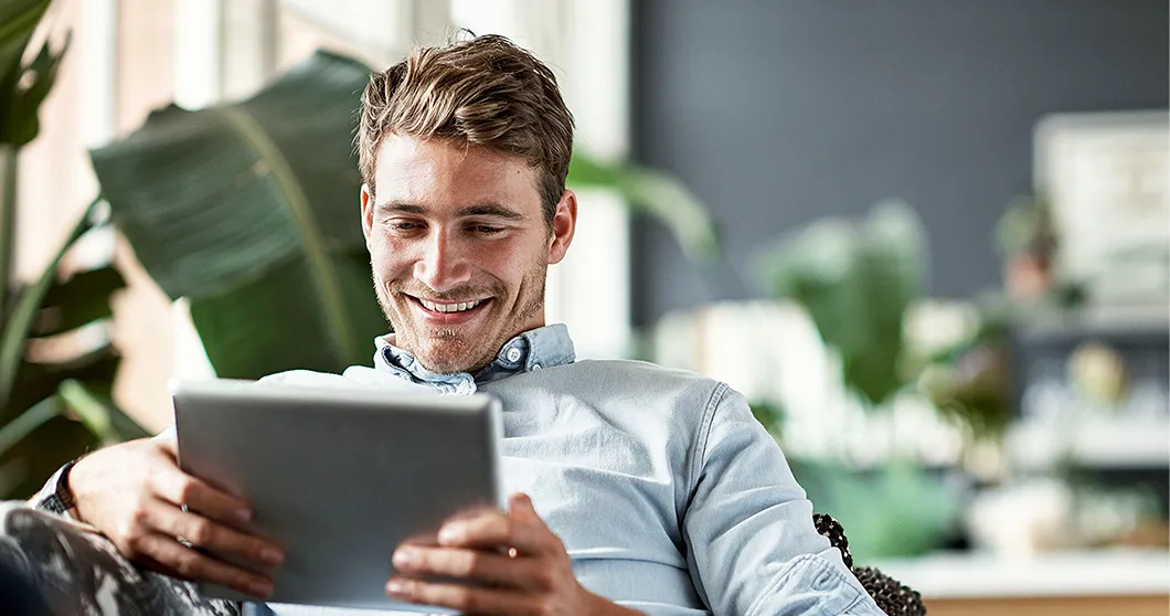 Glimlachende man kijkt op zijn tablet