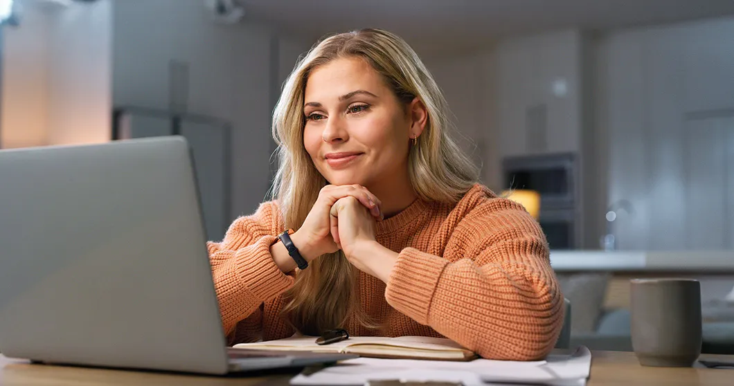Glimlachende vrouw kijkt naar haar laptop